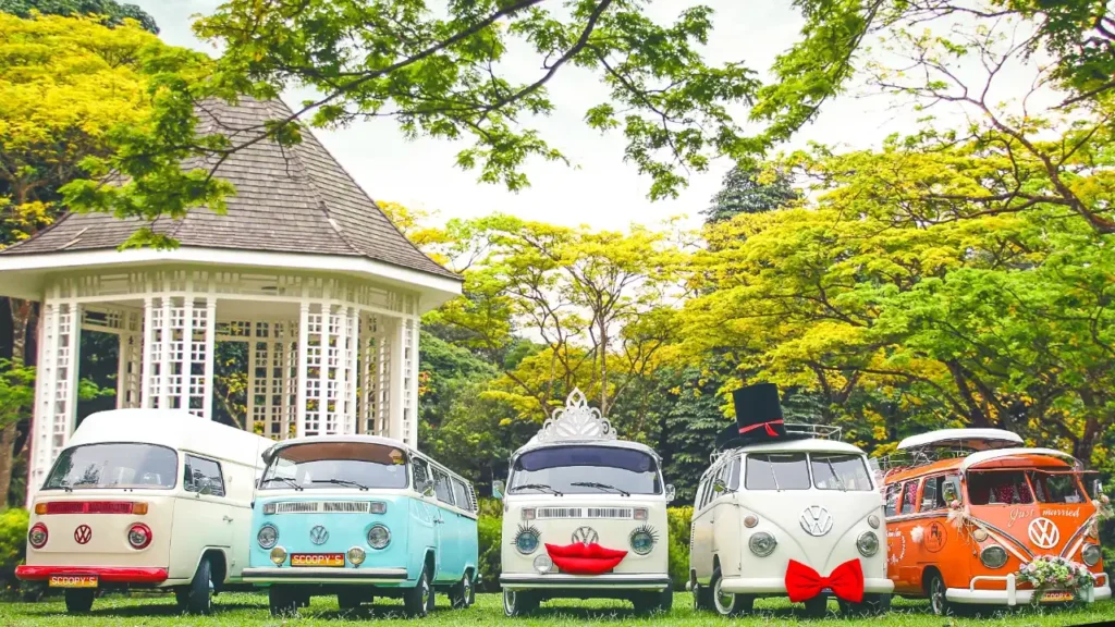 Five restored vintage Volkswagen Kombi vans from the Super Ice Cream Truck heritage fleet lined up in a Singapore garden, illustrating circular-economy adaptive reuse of classic vehicles