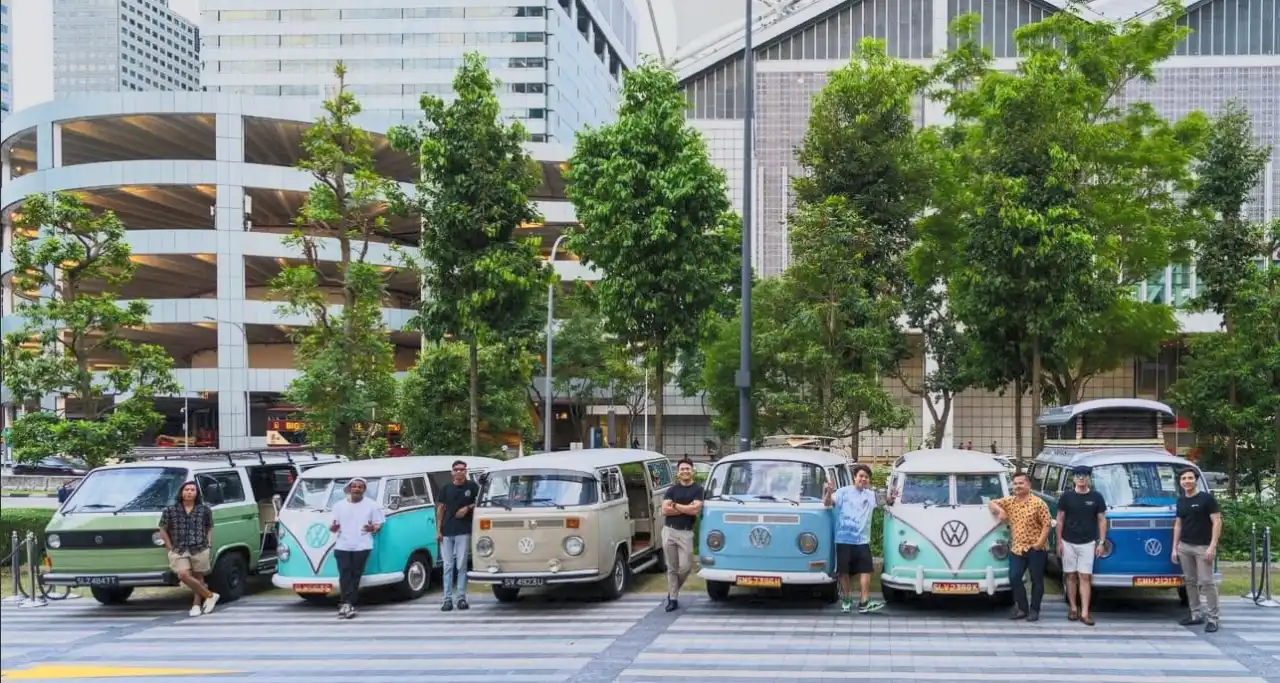 The Super Ice Cream Truck team standing with their restored vintage Volkswagen Kombi fleet at a Singapore city-centre brand activation, showing heritage vehicles kept in active service